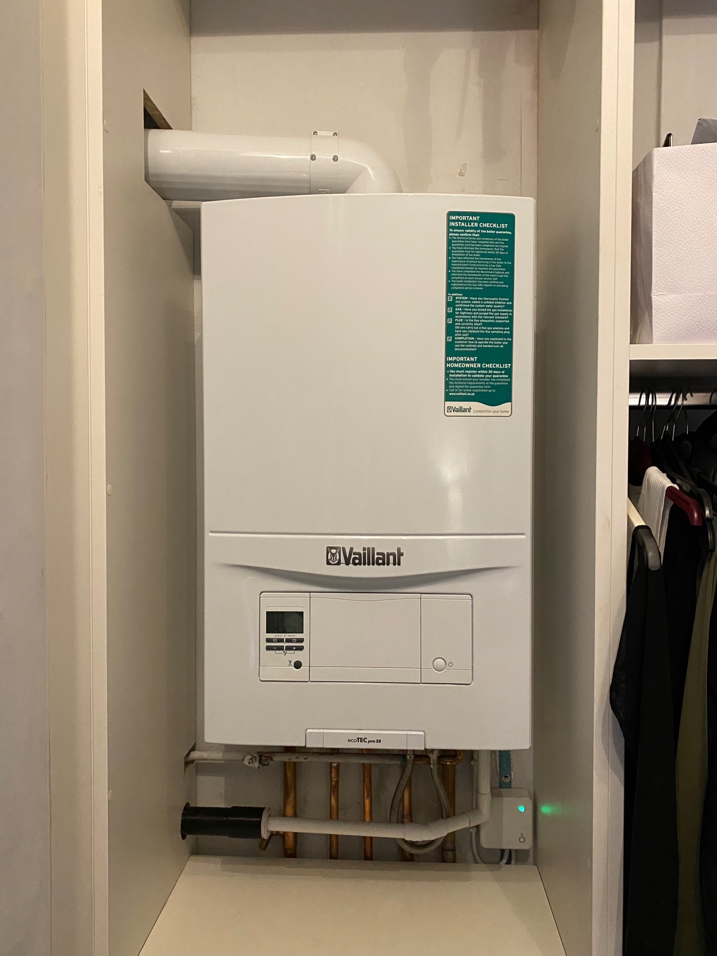 New Vaillant combi boiler installed in an airing cupboard with copper pipework below