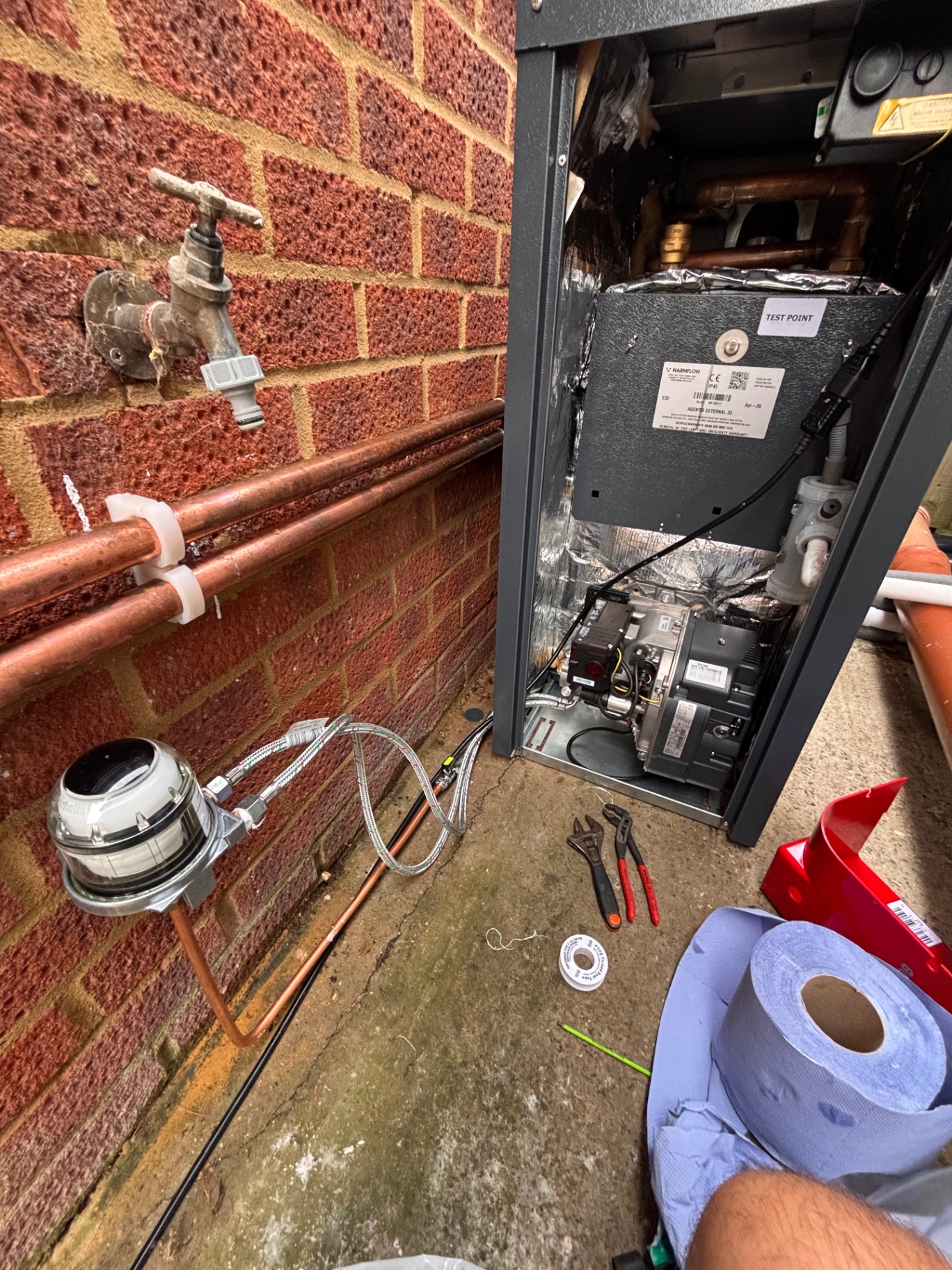 External boiler installation with copper pipework on a brick wall
