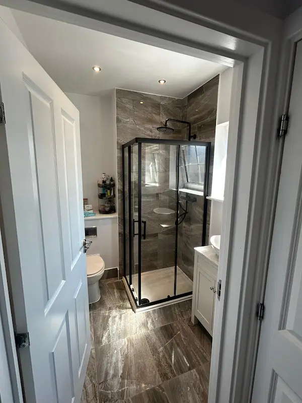 New shower room with black framed shower cubicle and marble-effect tiling