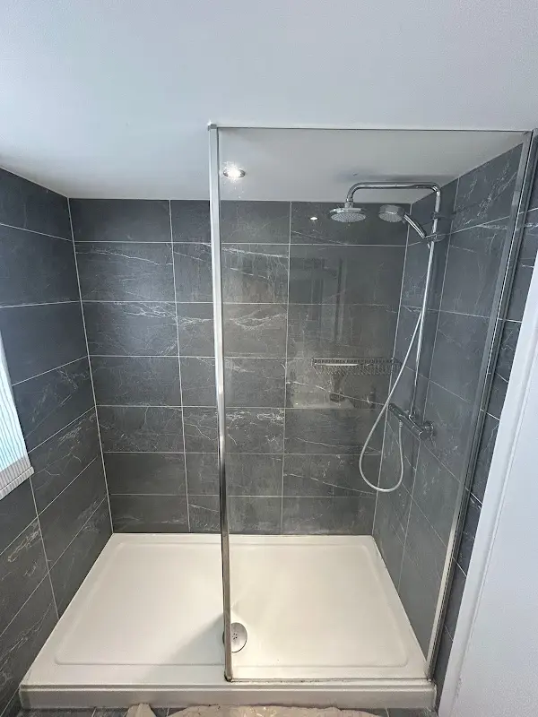 Walk-in shower with grey slate-effect wall tiles and glass screen