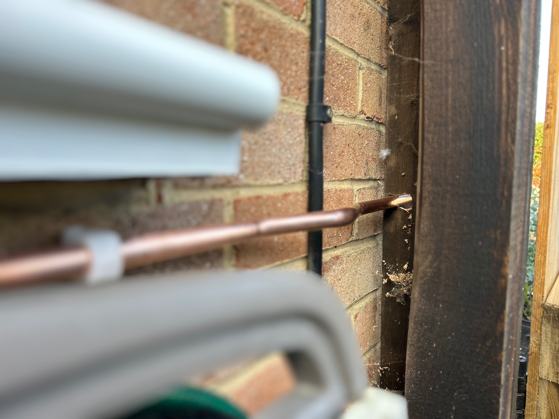 New copper pipework routed through a garden wall