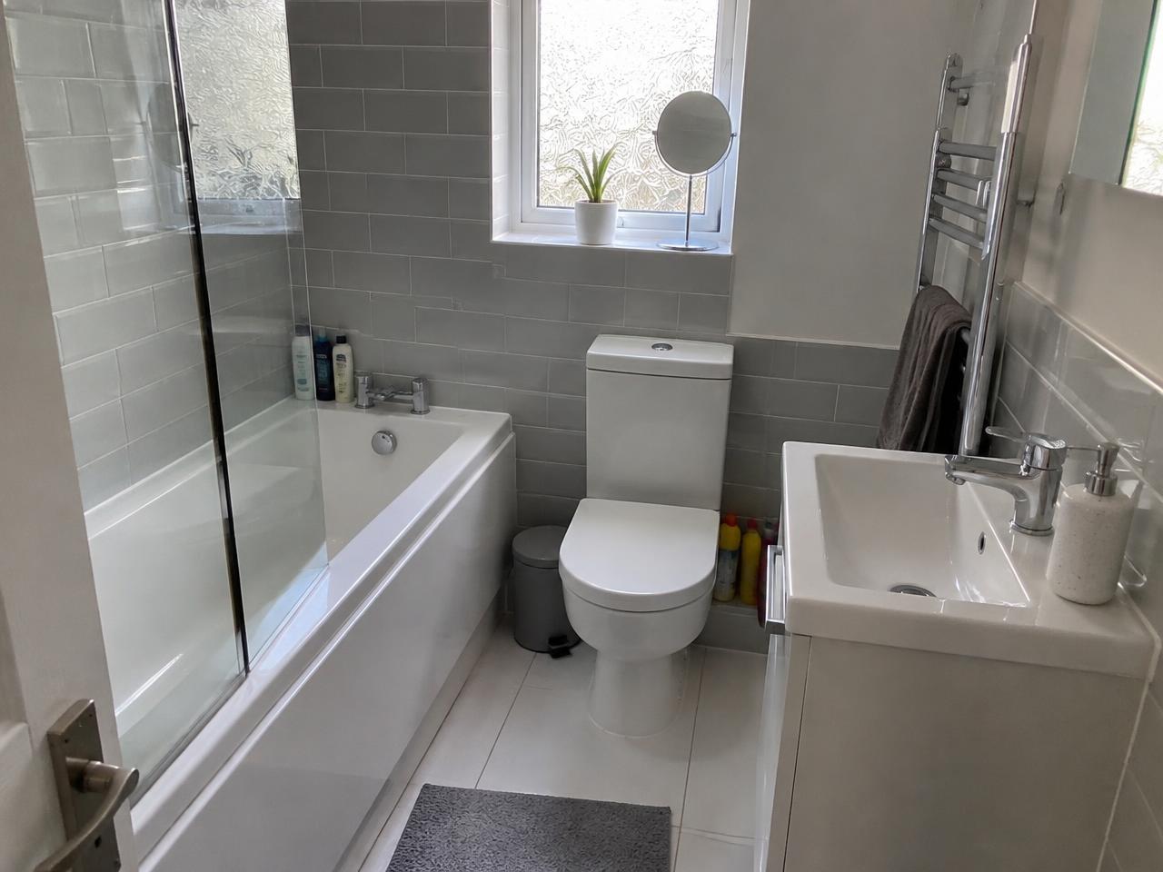 Modern grey tiled bathroom with walk-in shower and backlit round mirror